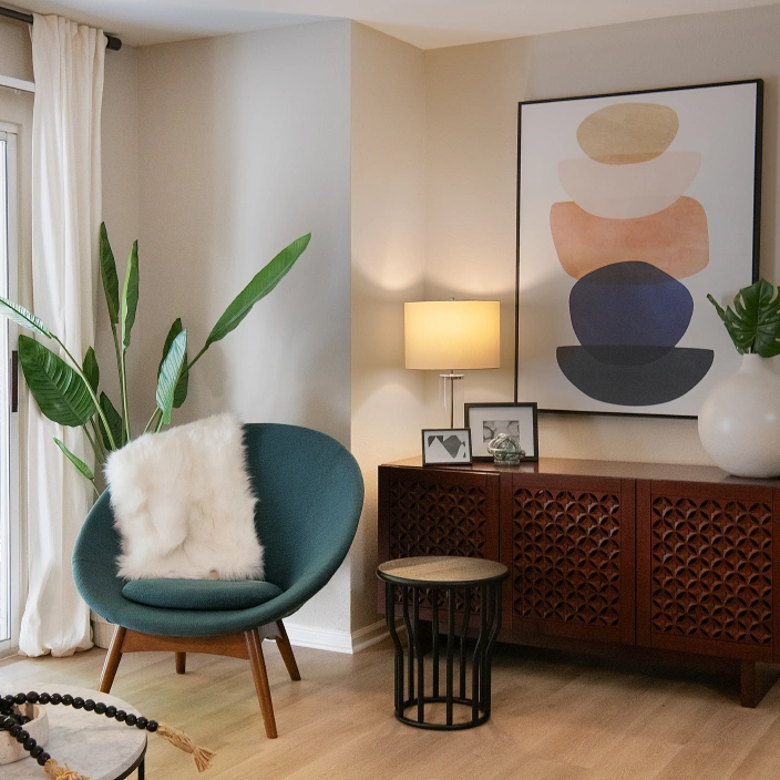 Living room corner with teal accent chair, decorative console, large artwork, and sliding patio doors