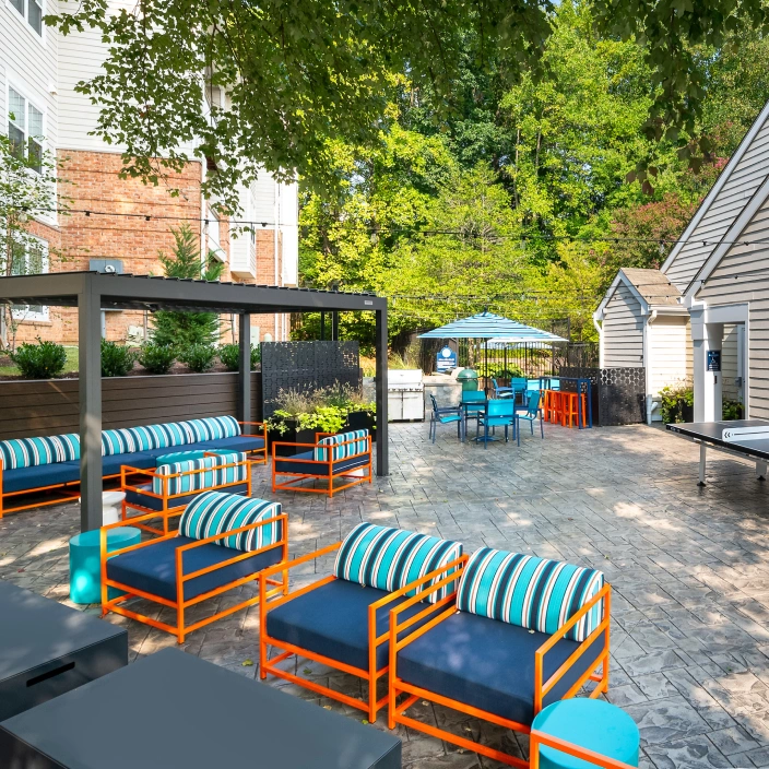 Outdoor community space with ping pong table, shaded seating, and vibrant blue dining furniture