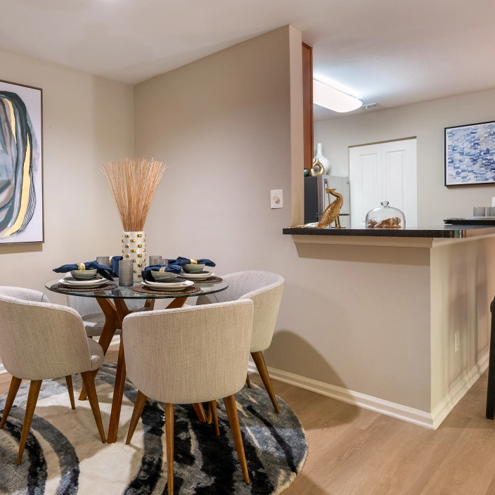 Modern dining nook with circular table, neutral chairs, and bold artwork above the setting