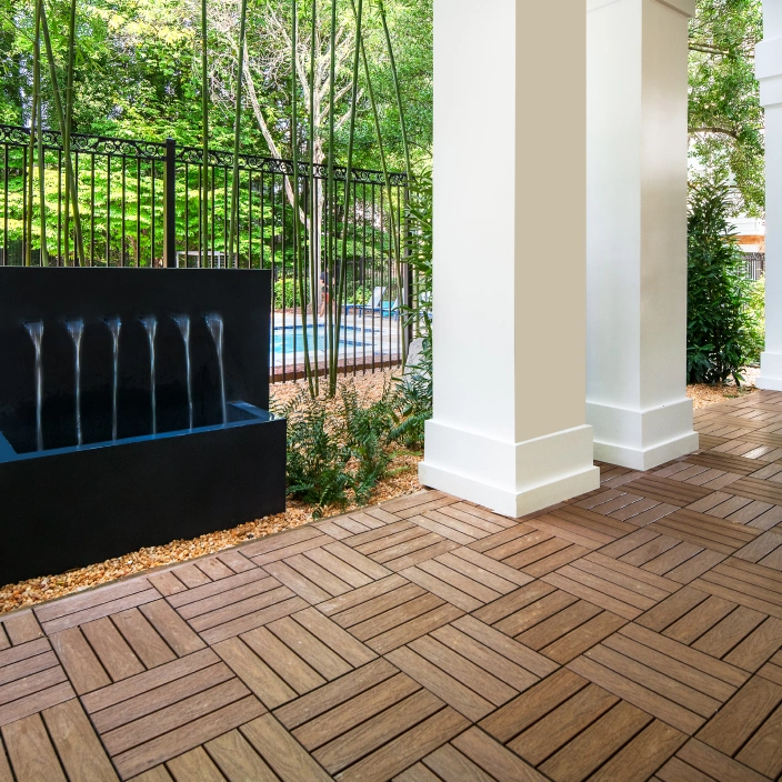 Zen garden with sleek rectangular water fountain and wooden tile flooring beside pool area