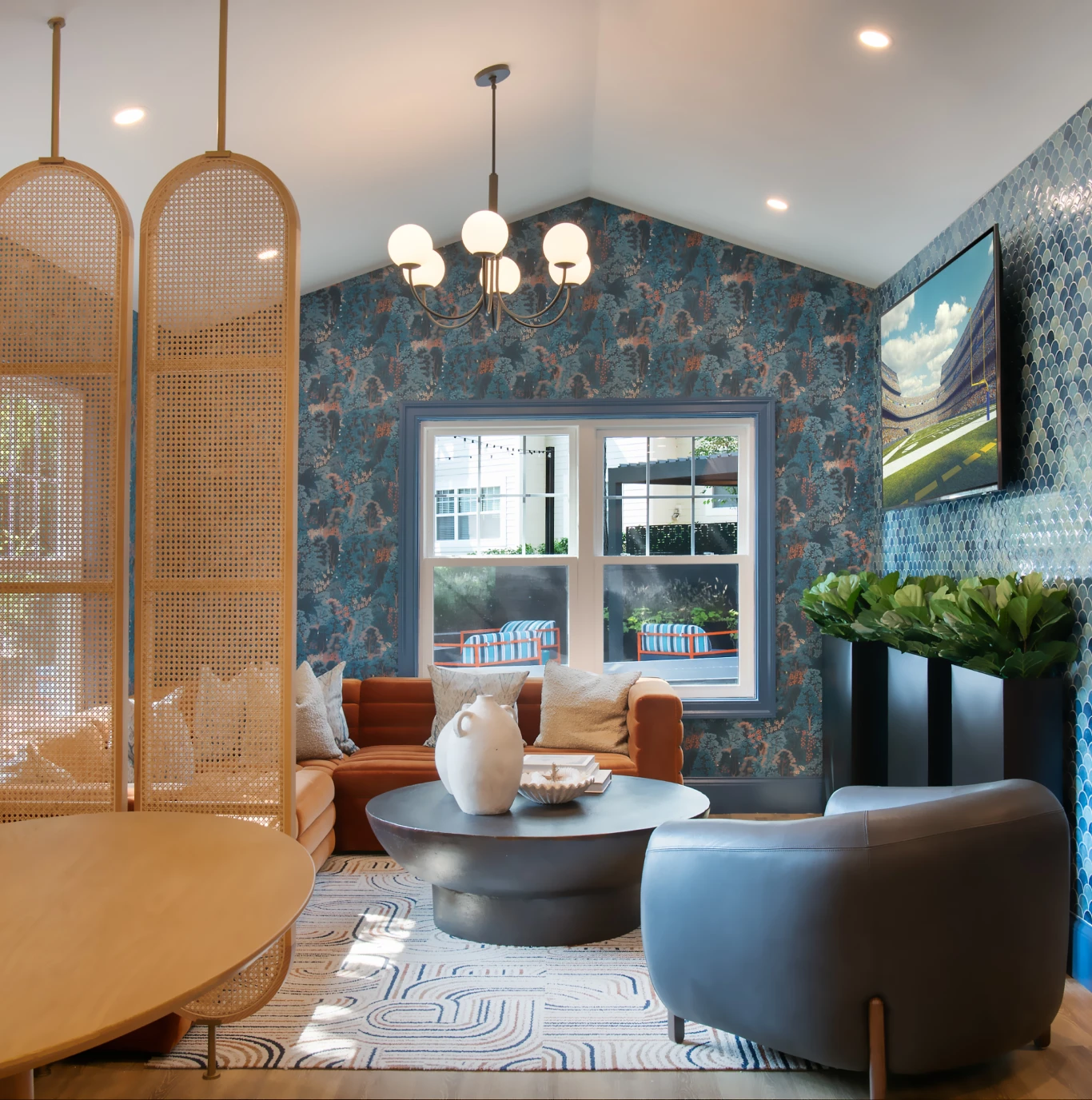 Modern living room with patterned wallpaper, cozy sectional sofa, round table, and decorative accents