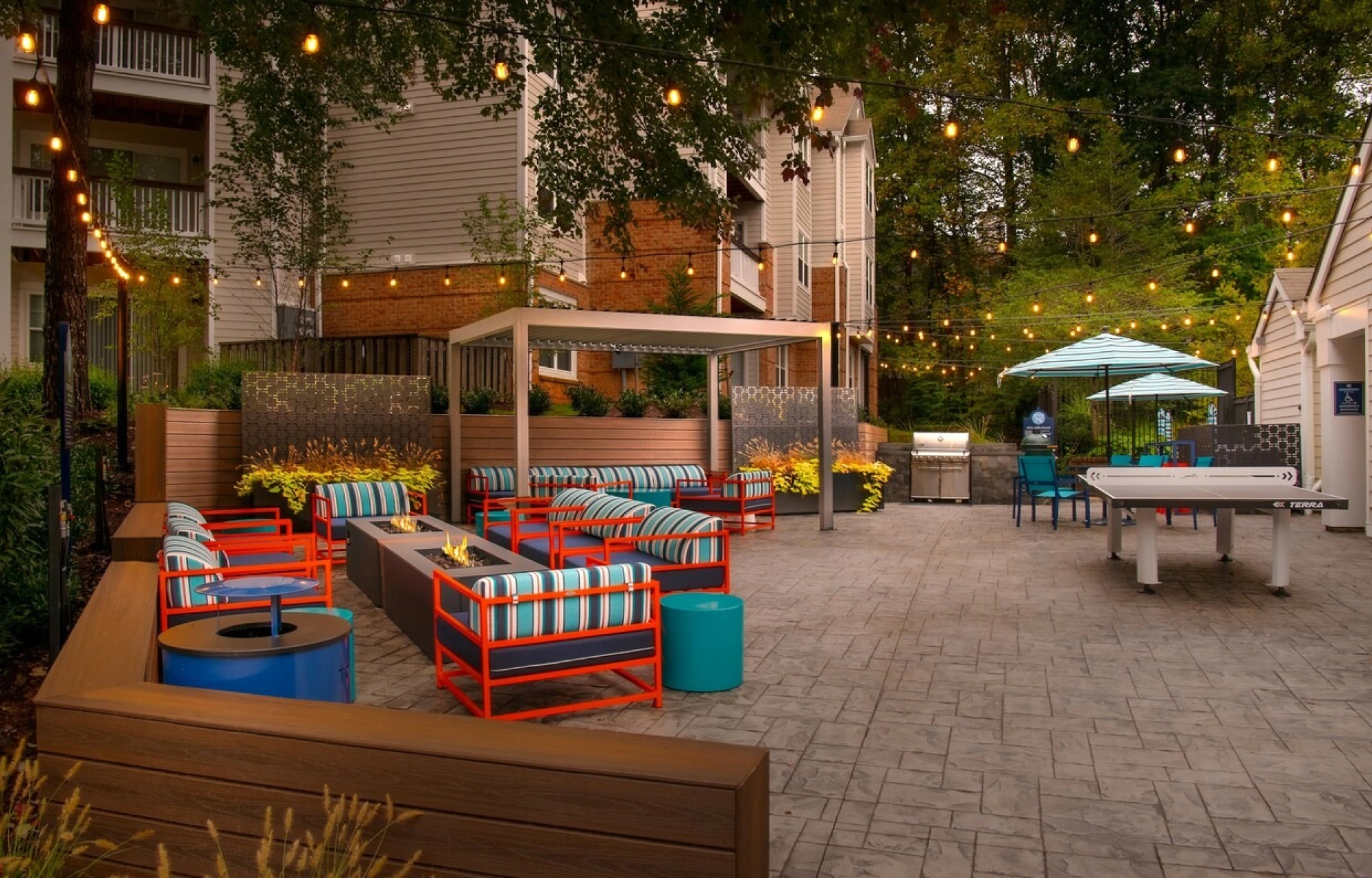 Modern outdoor lounge with fire pit seating, festive string lights, and covered cabana area